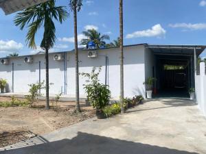 a white building with palm trees in front of it at Nhà nghỉ Thế Phú in Trà Vinh