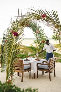 a man standing in front of a table with food at Kisiwa on the Beach in Paje