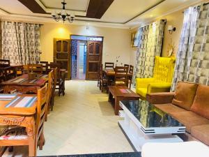 sala de estar con mesas y sofá amarillo en Villa Serene Hotel, en Kitale