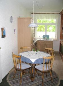 a table and chairs in a kitchen with a table and a window at Unterm-Reetdach-Whg-4-unten-rechts in Borkum