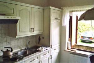 a kitchen with white cabinets and a sink and a window at Unterm-Reetdach-Whg-3 in Borkum