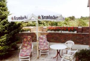 a patio with a table and chairs and an umbrella at Unterm-Reetdach-Whg-3 in Borkum