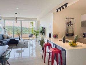 Una cocina y una sala de estar con dos taburetes de bar rojos. en Luxury Beachfront Apartment Near Panama City, en ArraijÃ¡n