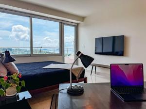 Un dormitorio con una cama y un ordenador portátil sobre una mesa. en Luxury Beachfront Apartment Near Panama City, en ArraijÃ¡n