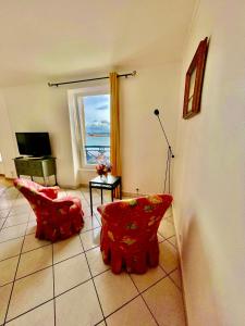 a living room with two red chairs and a window at La Langouste ROUGE in Camaret-sur-Mer