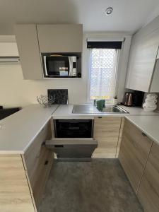 eine Küche mit Spüle und Mikrowelle in der Unterkunft Camping Del Mar 264, Mobile Home Excellence, 3 chambres, 6 personnes, 2 Salles de Bain, bord de mer in Argelès-sur-Mer + 15 Fotos