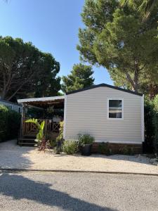 ein kleines weißes Haus mit einer Veranda in der Unterkunft Camping Del Mar 264, Mobile Home Excellence, 3 chambres, 6 personnes, 2 Salles de Bain, bord de mer in Argelès-sur-Mer