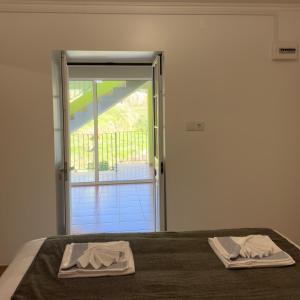 a bed with two towels sitting on top of it at Green House in Calheta