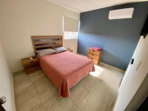 a small bedroom with a bed with a pink blanket at Departamento Piso 2 in Mazatlán