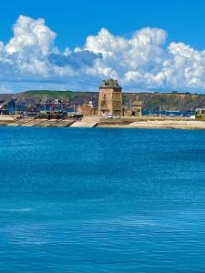 a large body of blue water with a building in the background at La Langouste ROUGE in Camaret-sur-Mer +39 photos