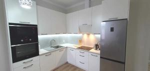 a kitchen with white cabinets and a stainless steel refrigerator at Apartament Chłodna 14 in Suwałki