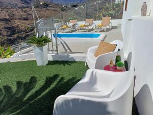 a patio with white chairs and a table with wine bottles at DRAGO 100, quiet and friendly in Telde