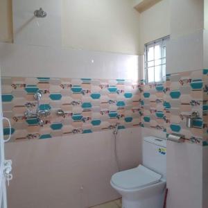 Un baño con inodoro y una pared de azulejos. en Pokhara Apartment CS, en Pokhara