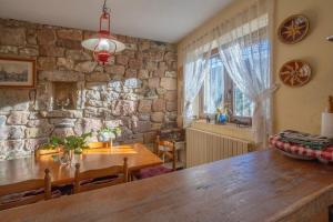 ein Esszimmer mit einem Tisch und einer Steinwand in der Unterkunft El Casuco in Santa María de Redondo