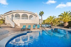 a swimming pool with blue chairs and a house at Villa Quesada in Rojales