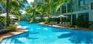 a swimming pool in front of a building with palm trees at Modern Condo at Diamond Resort in Bang Tao Beach +6 photos