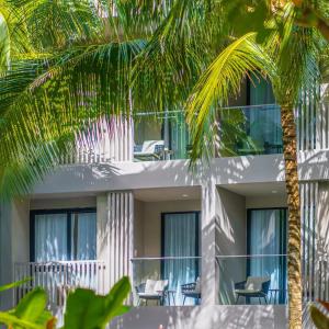 a building with chairs and palm trees in front of it at Modern Condo at Diamond Resort in Bang Tao Beach