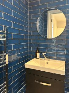a blue tiled bathroom with a sink and a mirror at Keysan House 1 in London