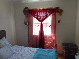 une chambre avec un rideau rouge et une fenêtre dans l'établissement Kenda house, au Cap