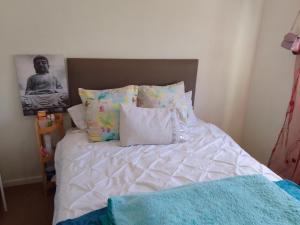 un lit avec des draps blancs et des oreillers dans une chambre dans l'établissement Kenda house, au Cap