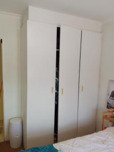 une chambre avec des murs blancs et un lit et un placard dans l'établissement Kenda house, au Cap