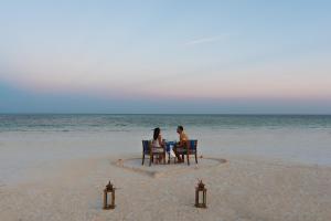 two people sitting at a table on the beach at Kisiwa on the Beach in Paje