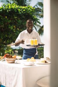 a man holding a tray of food on a table at Kisiwa on the Beach in Paje