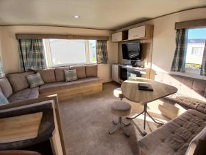 a living room with a couch and a table at Gold Plus Caravan in Dymchurch