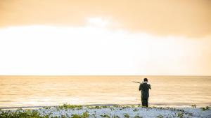 a man standing on a beach looking at the ocean at Kisiwa on the Beach in Paje