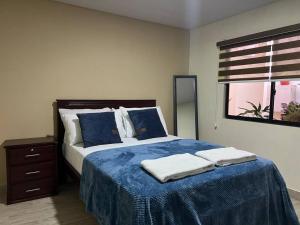 sypialnia z łóżkiem z niebieskimi prześcieradłami i oknem w obiekcie Sanctuary Apartment 5 bedroom 4 bathroom w Baños
