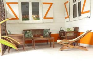 a porch with two benches and a table and chairs at Villa Ti Gîte - Piscine privée in Le Marin