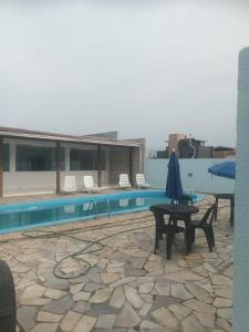 eine Terrasse mit einem Tisch und einem Sonnenschirm neben einem Pool in der Unterkunft Casa na praia in Pontal do Paraná