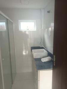 ein weißes Badezimmer mit Waschbecken und Dusche in der Unterkunft Casa na praia in Pontal do Paraná