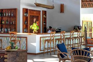 a restaurant with a bar with chairs and a person in the background at Kisiwa on the Beach in Paje