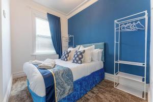 a blue bedroom with a bed with a blue wall at The Bell's Self-Service Holiday Flat Bournemouth in Bournemouth