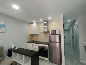a kitchen with a stainless steel refrigerator and a table at Arenas 50, 100 mt d playa ingles in Playa del Ingles