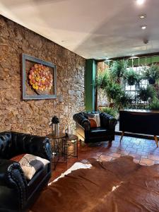 a living room with leather furniture and a stone wall at Hotel Solar da Beira in São Francisco do Sul +52 photos