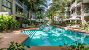 a swimming pool in the middle of a building with palm trees at Modern Condo at Diamond Resort in Bang Tao Beach