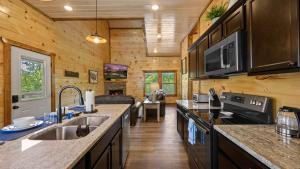 una cucina con pareti in legno e pavimenti in legno in una baita di tronchi di Liberty Lodge - Family Getaway with Pool, Hot Tub, Arcade & Dogs a Pigeon Forge