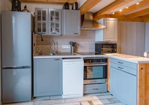 a kitchen with white cabinets and a stainless steel refrigerator at Rare, Triplex 12 personnes, accès direct ski aux pieds in Les Deux Alpes +12 photos