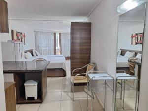 ein Zimmer mit zwei Betten und eine Küche mit Stühlen in der Unterkunft Apartamento BLUE in João Pessoa