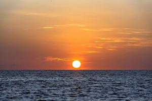 a sunset over the ocean with the sun in the sky at Kisiwa on the Beach in Paje