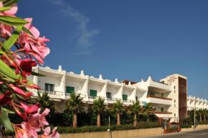 un edificio bianco con palme di fronte di Cala Saracena Resort a Torre Vado
