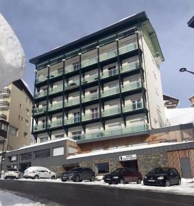 Un gran edificio con coches aparcados delante. en Appartement cosy à Bagnères-de-Bigorre, 34 m² avec balcon, en La Mongie 5 fotos más