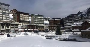 Una ciudad cubierta de nieve con edificios al fondo. en Appartement cosy à Bagnères-de-Bigorre, 34 m² avec balcon, en La Mongie