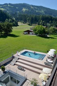 an outdoor swimming pool with a large green field at Wohlfühlhotel Schiestl in Fügen