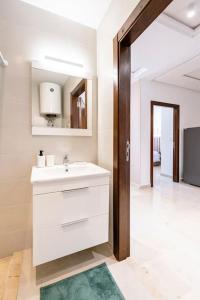 a white bathroom with a sink and a mirror at City Hideaway Suite - TGV Station & Beach Walk in Tangier