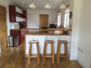 a kitchen with three wooden stools at a counter at Beolary in Oban +40 photos