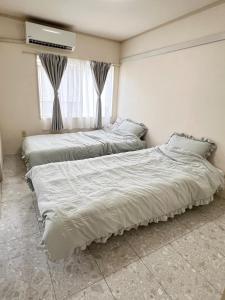 two beds sitting in a room with a window at Chigasaki JH Court C - Vacation STAY 17903 in Chigasaki