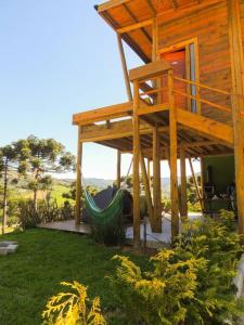 a hammock in front of a house with a deck at Cabana Mendoza - Busch Camping in Rancho Queimado